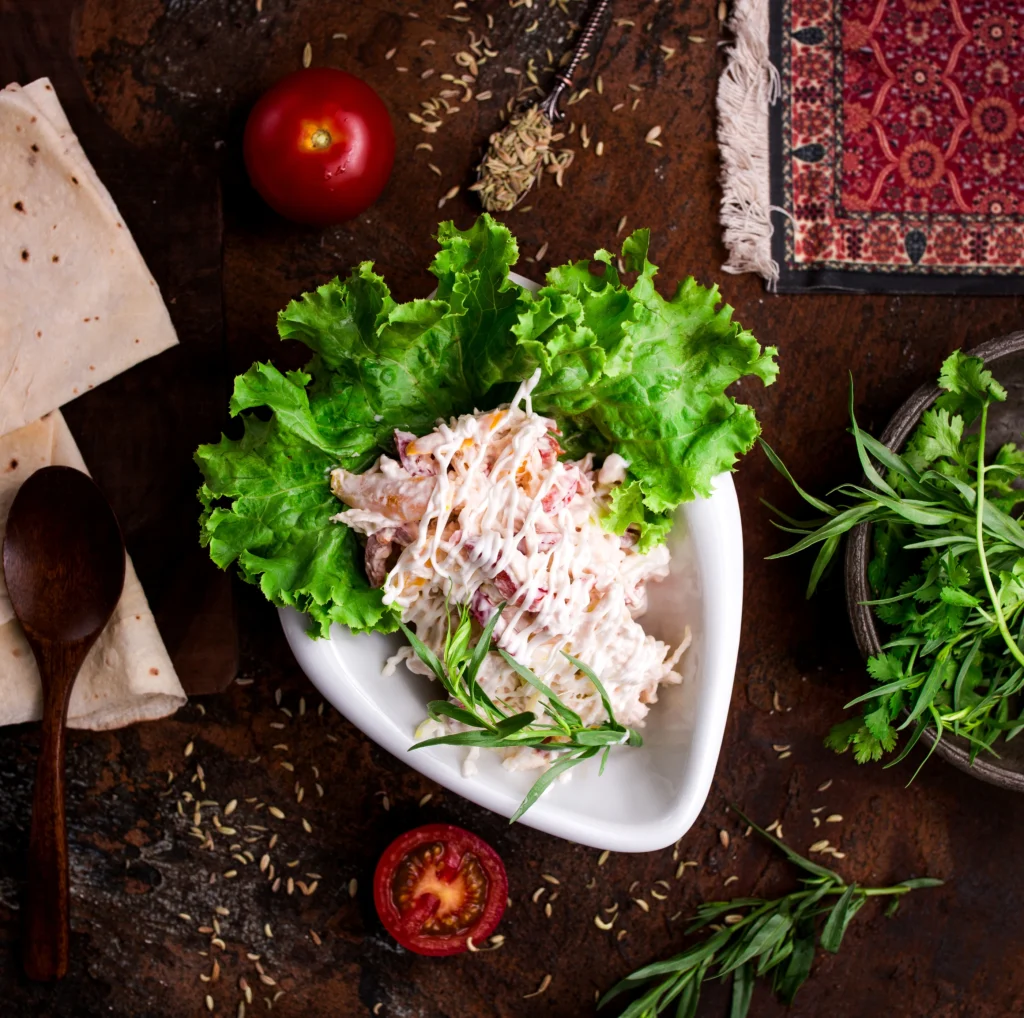 A bowl of creamy chicken salad made at home using a famous recipe served with crackers and lettuce